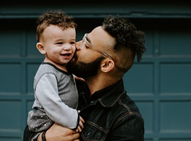 Loving dad kissing smiling baby cheek