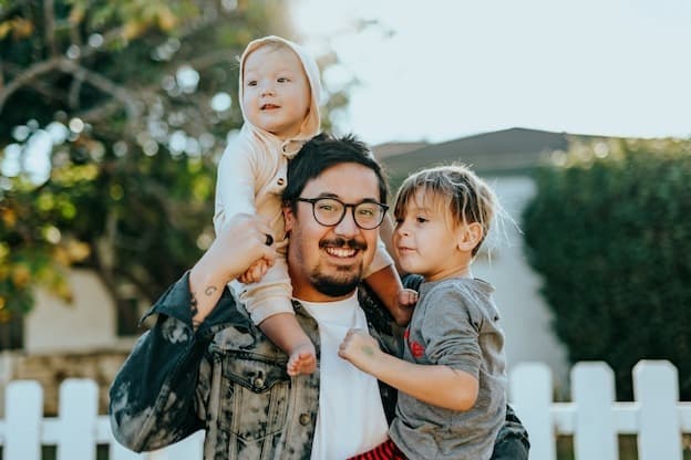 Happy father playing outdoors carrying his kids