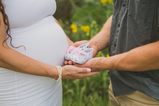 Parents holding tiny newborn booties against baby bump