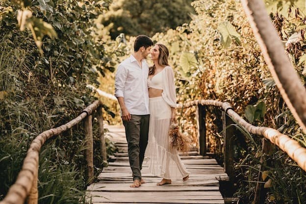 Couple sharing laugh on wooden bridge surrounded by forest